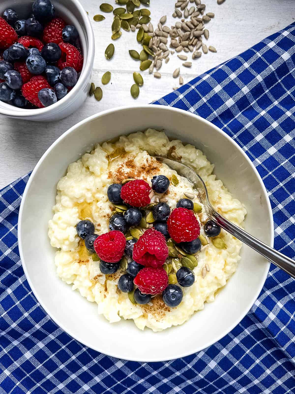 bowl of creamy rice pudding topped with fruit, nuts, seeds and honey.
