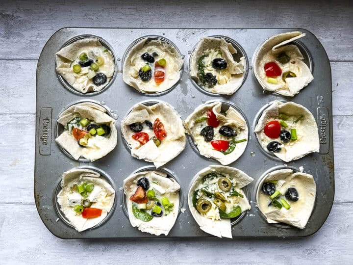mini tortilla muffins filled and ready for the oven in a muffin tin.