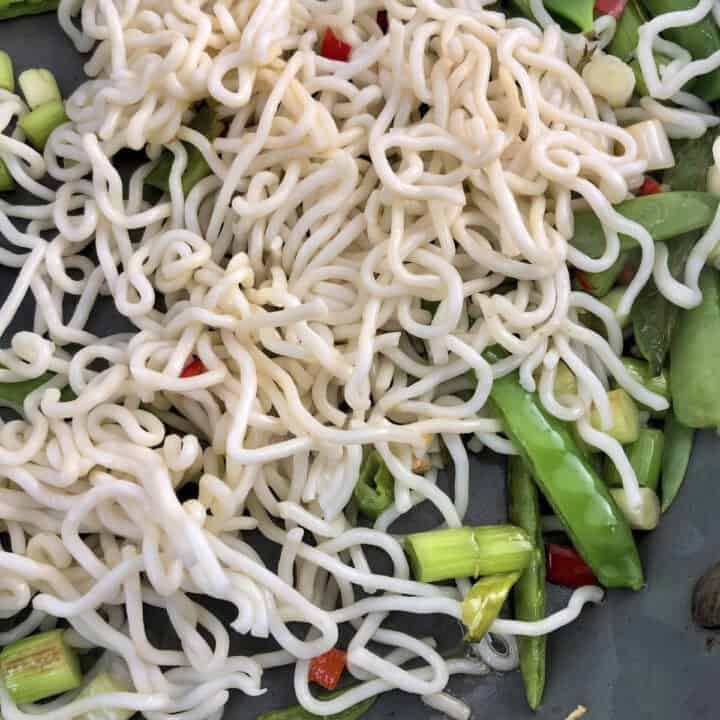 asian noodles and crunchy vegetables frying in wok for smoked mackerel salad.