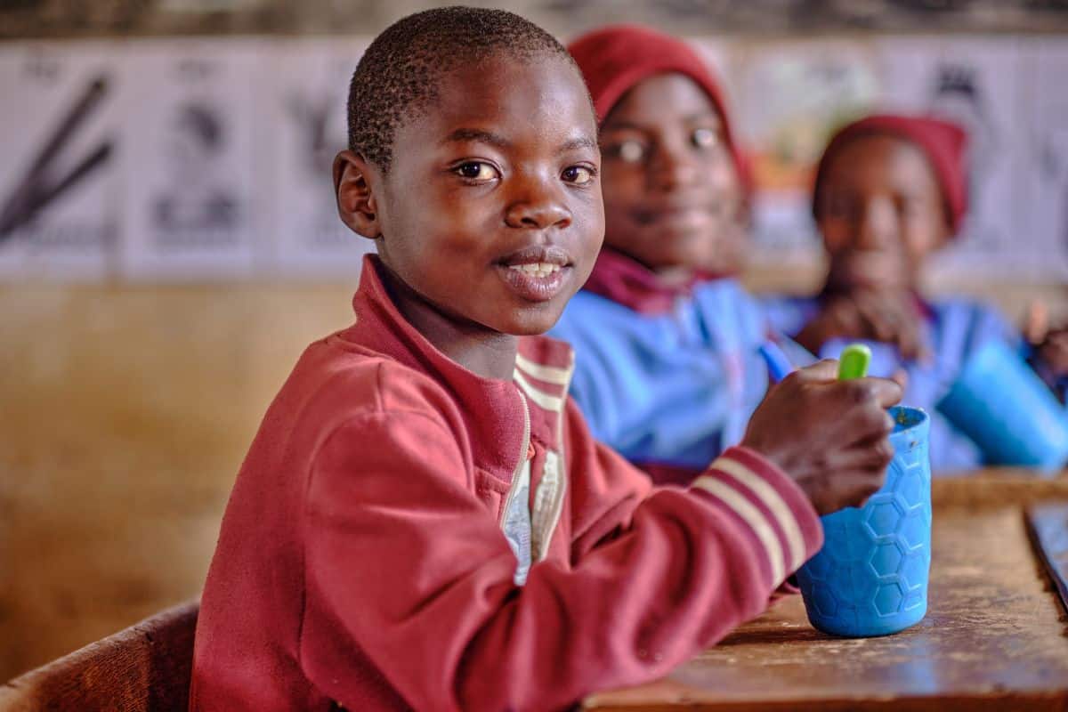 boy sitting at a table eating mary's meals with two boys in background