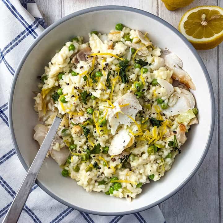 smoked haddock risotto in bowl topped with lemon zest, parsley and black pepper.